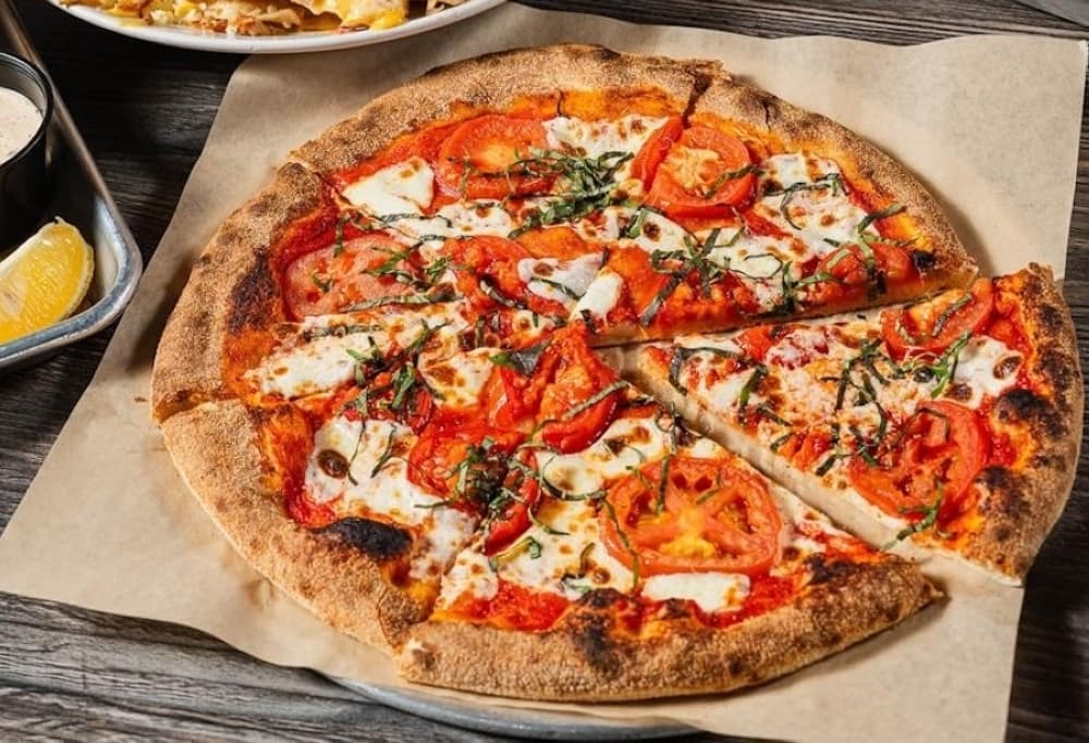 A pizza with tomatoes, basil and fresh mozzarella