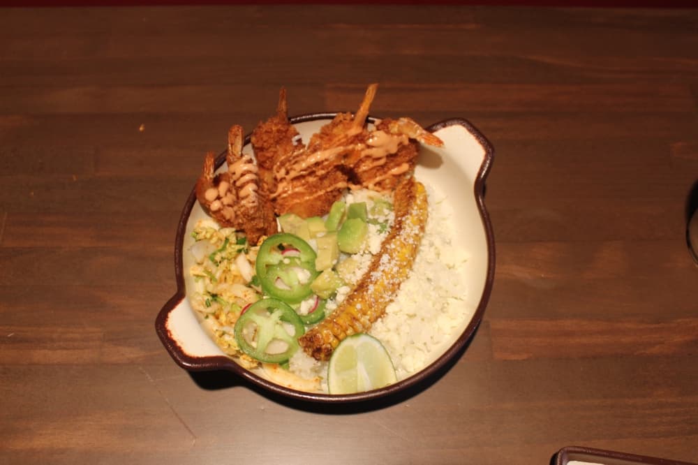 The Crispy Shrimp Bowl is available at Comidas y Leche in Puss in Boots Del Mar land at the resort. It includes crispy shrimp, cilantro-lime rice, cabbage slaw, corn, avocado, jalapeño, radish, tomato aioli and queso fresco. (Samantha Douty/Community Impact)