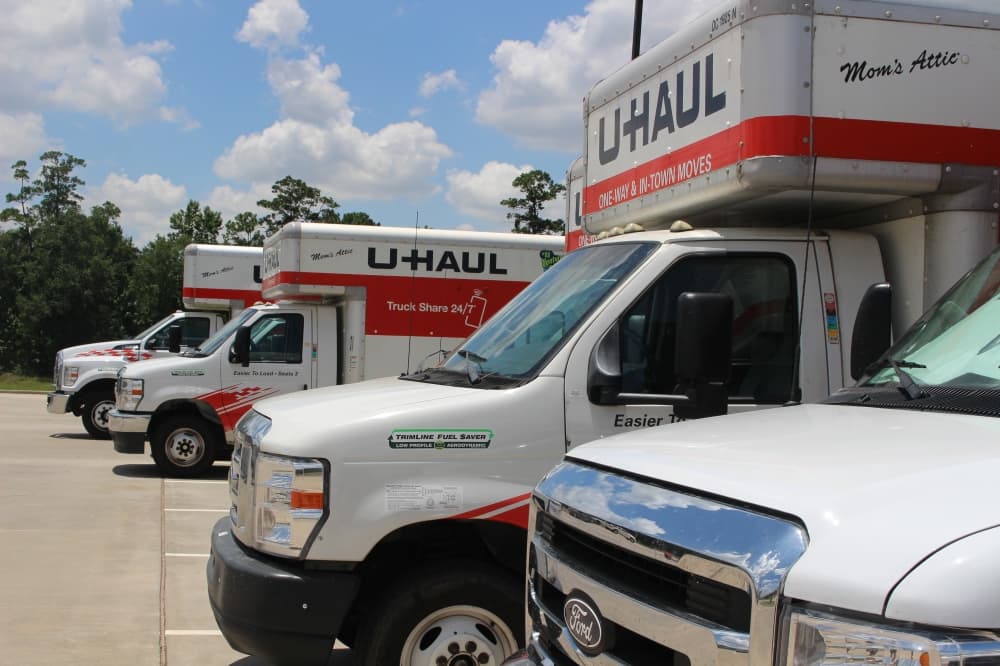 Side view of white and orange U-Haul trucks parked outside J&R's Ace Hardware