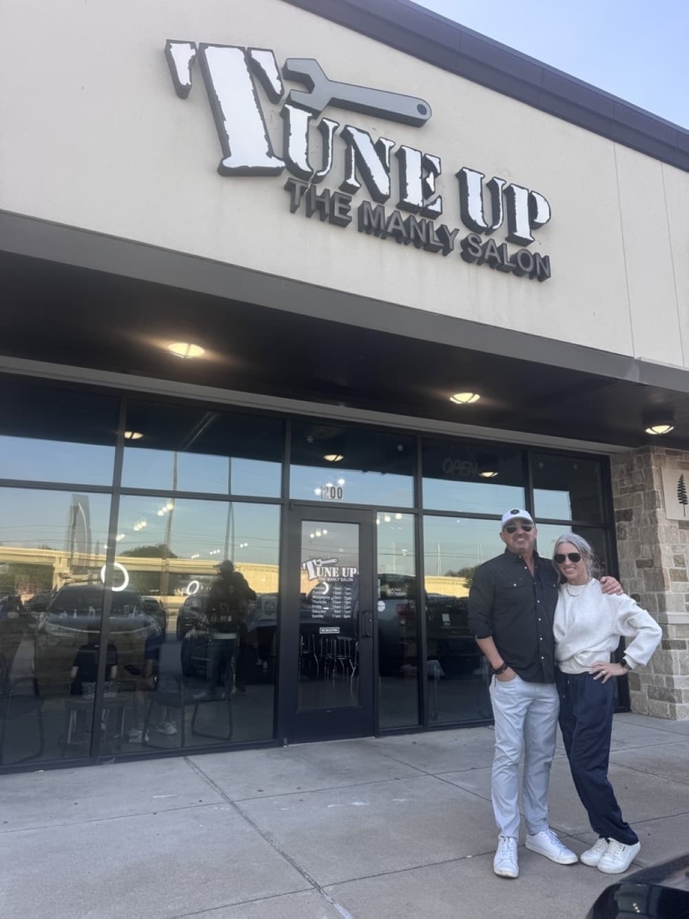 Amber and Brody Farris standing in front of a Tune Up Manly Salon