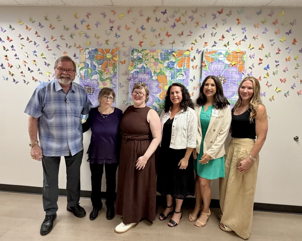 group of six people in front of a mural
