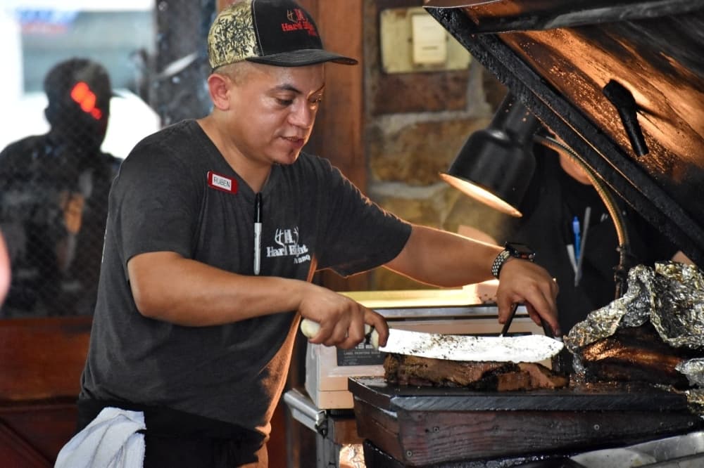 worker cutting brisket 