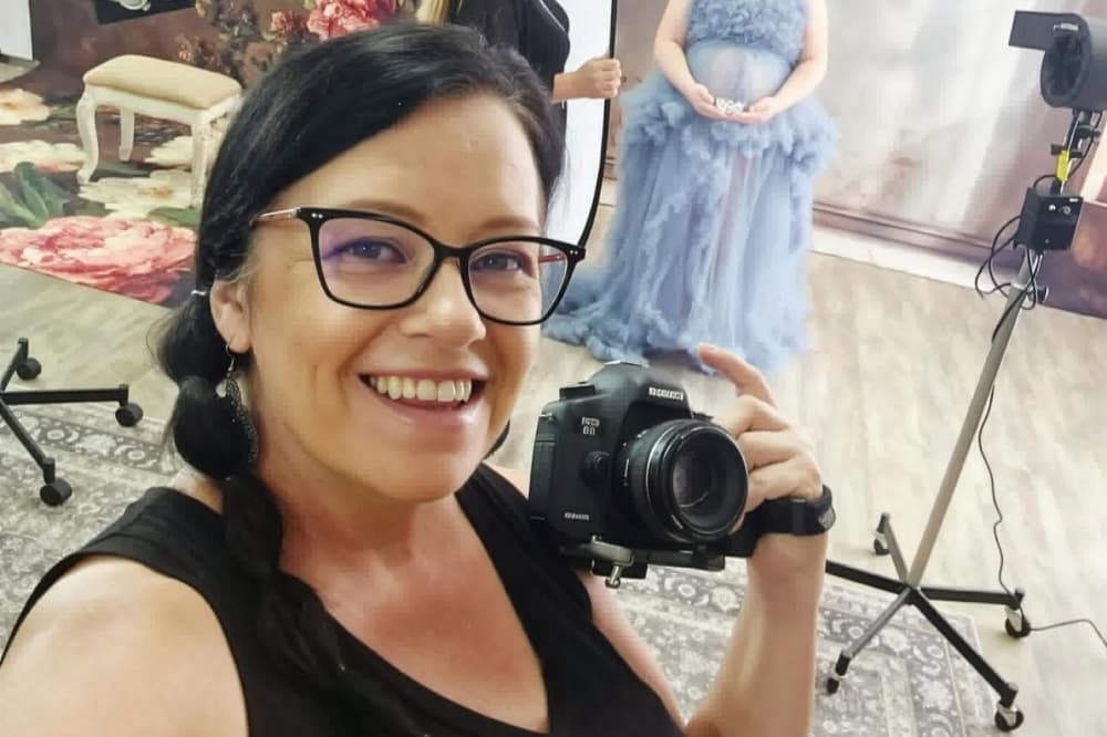 Woman in a black tank top holding a camera