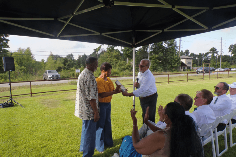 mayor presenting a plaque to two residents