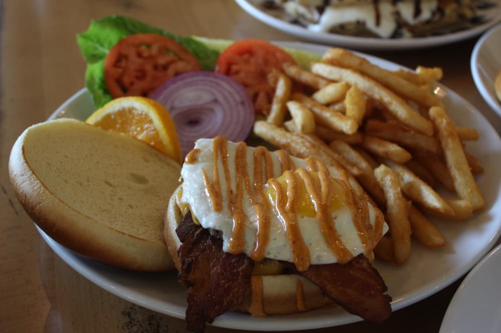 A breakfast burger with cheese, 2 strips of bacon, a sunny side up egg and chipotle mayo.