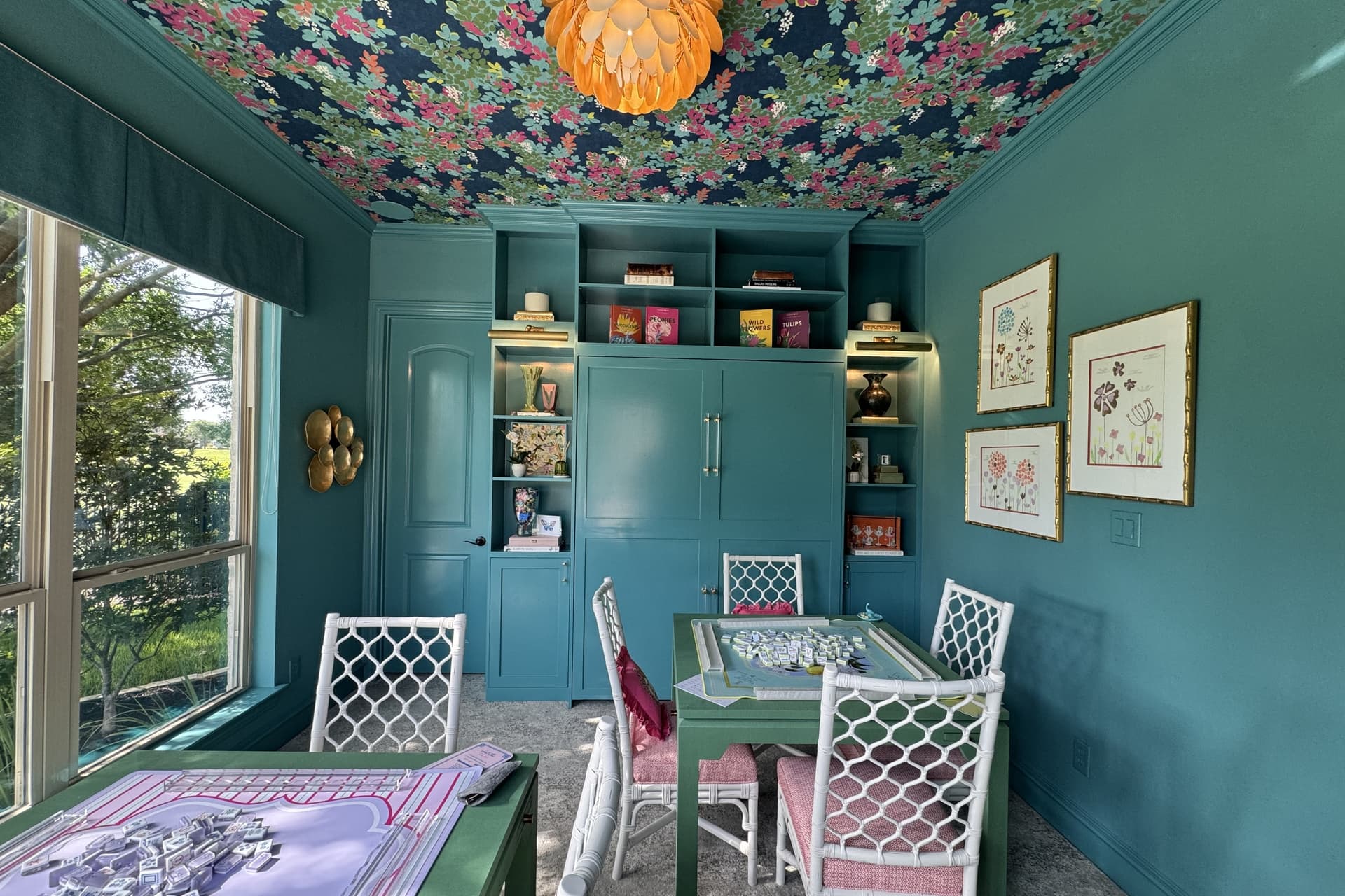 A blue room with pink chairs and green mahjong tables designed by Barbies House.