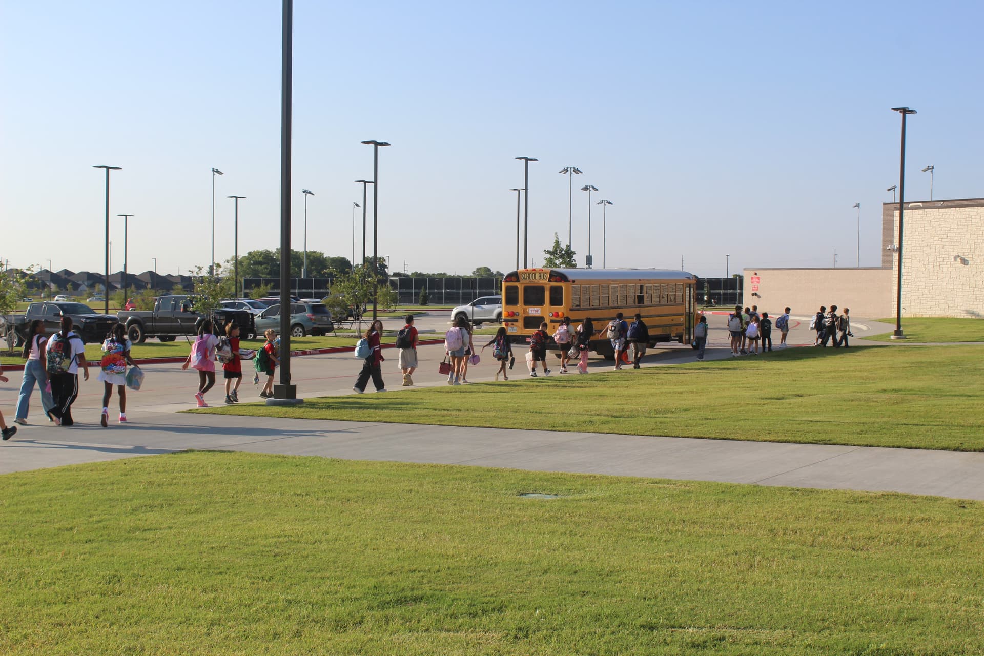 Students walk into Willard Middle School as a bus drives by in the background