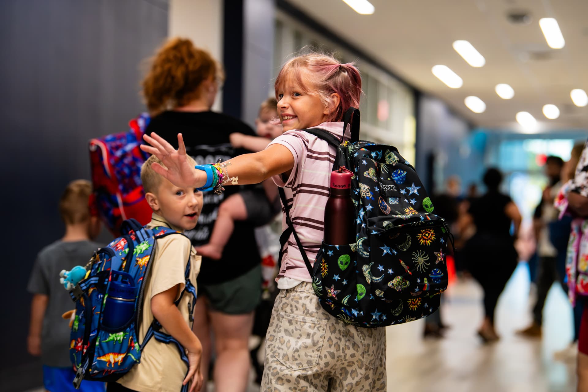 A student waves in the halls of Borman Elementary School during the first day of school on Aug. 13. (Sara Carpenter/Community Impact)