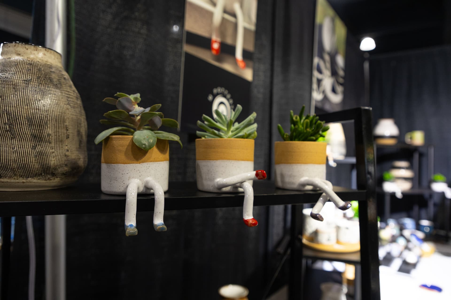 A row of small potted plants with legs sitting on a shelf.