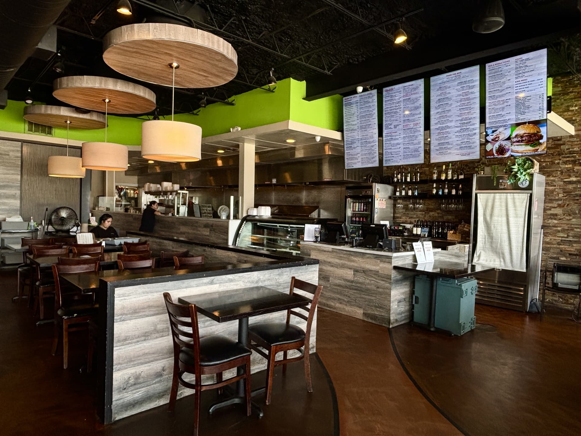 Interior photo of Saba's Grill & Wok, modern light fixtures hang from the ceiling, the restaurant's space follows a modern dark wood and paneled theme with painted green walls