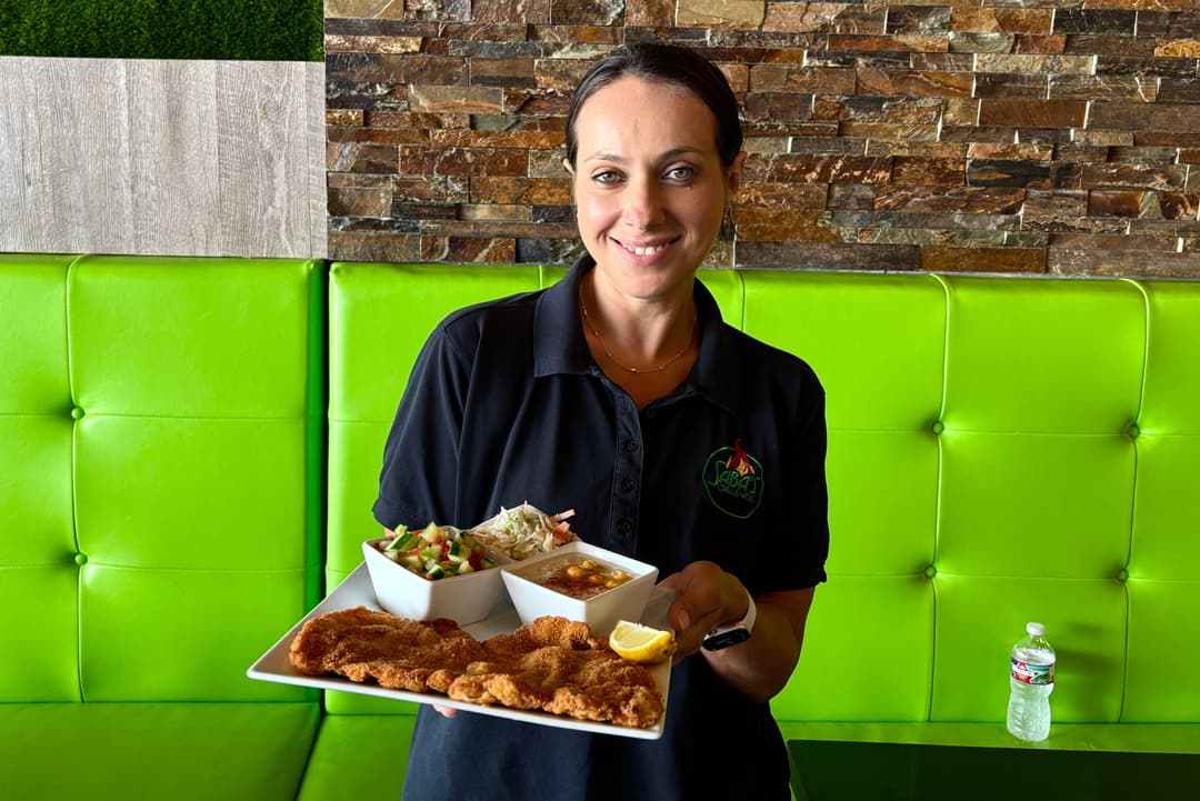 Headshot of Natalie Cohen, she is holding Saba's Grill & Wok's Schnitzel Plate