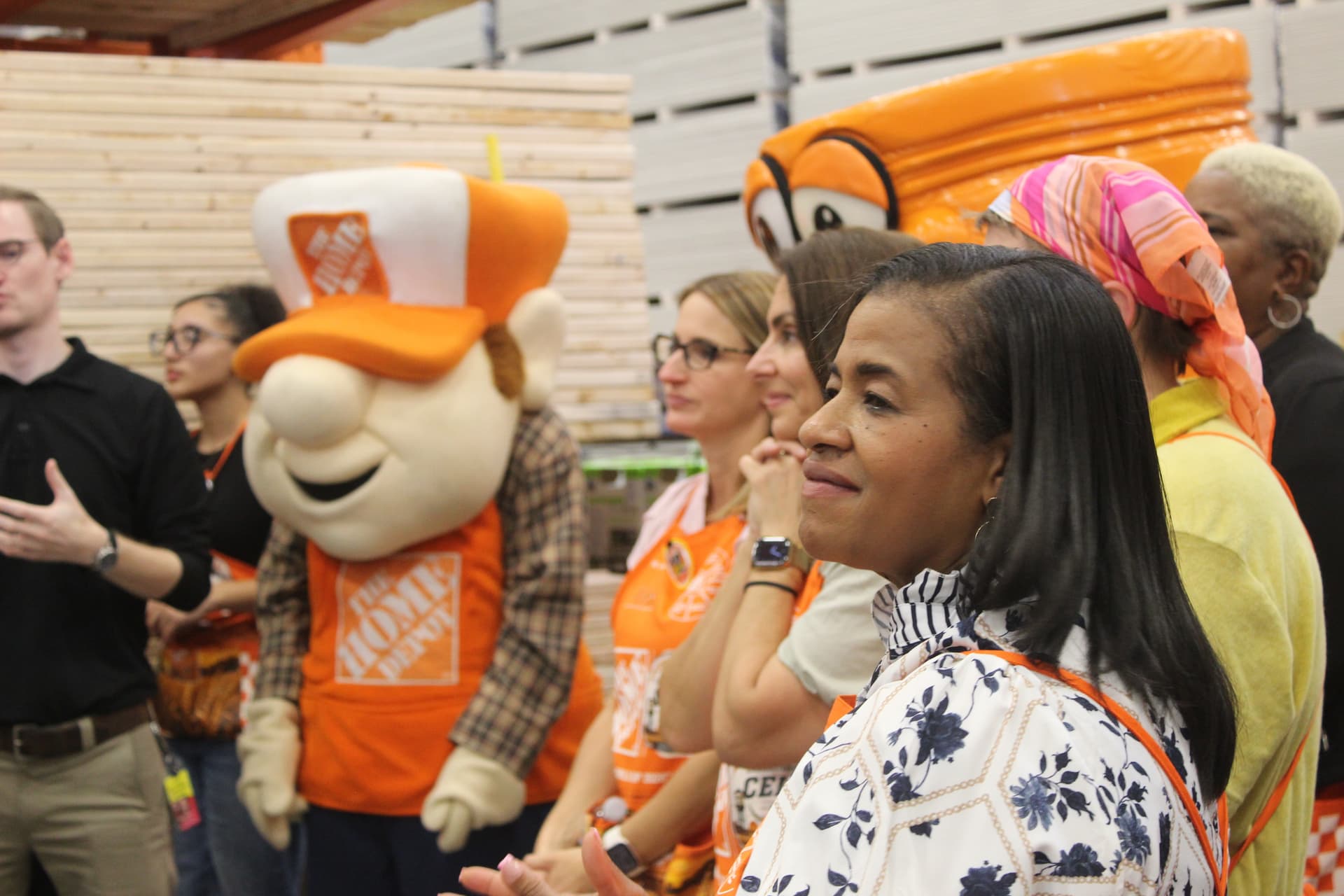 A crowd including a mascot with an orange vest and hat