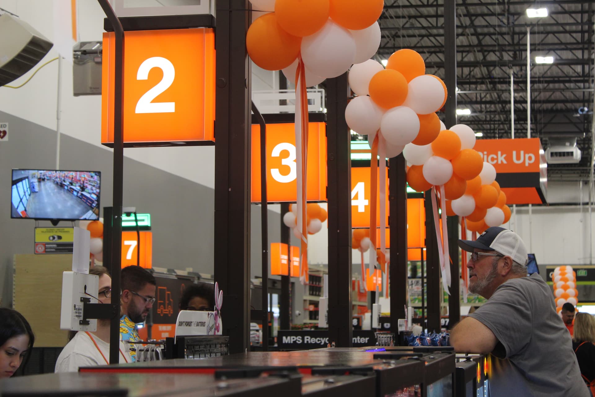 A self checkout area with orange signs and orange and white balloons