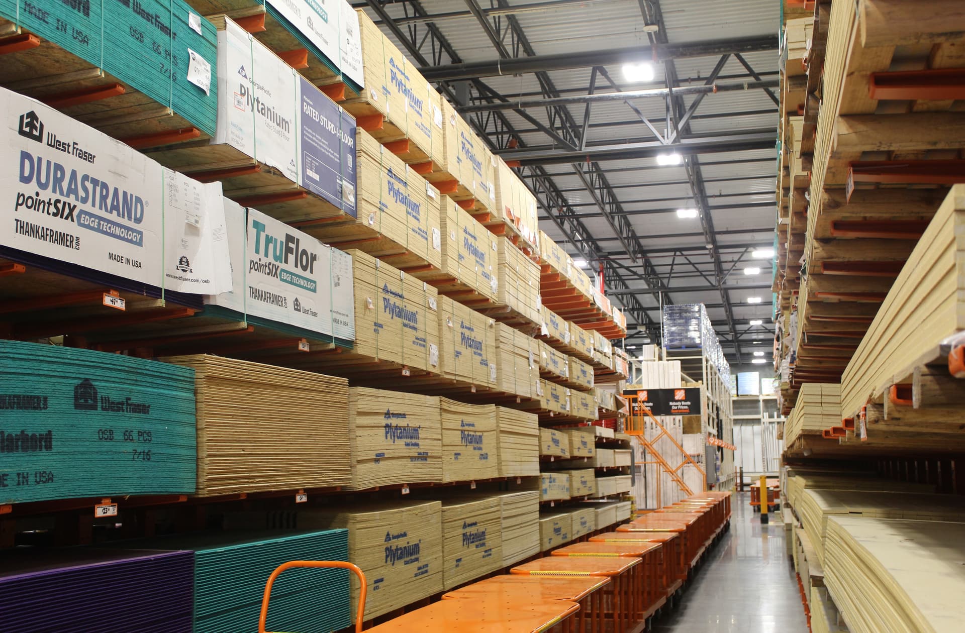 A lumber aisle with orange carts down the middle