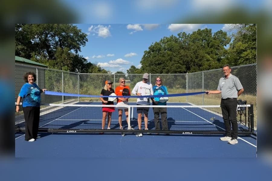 People cutting a ribbon on a pickleball court