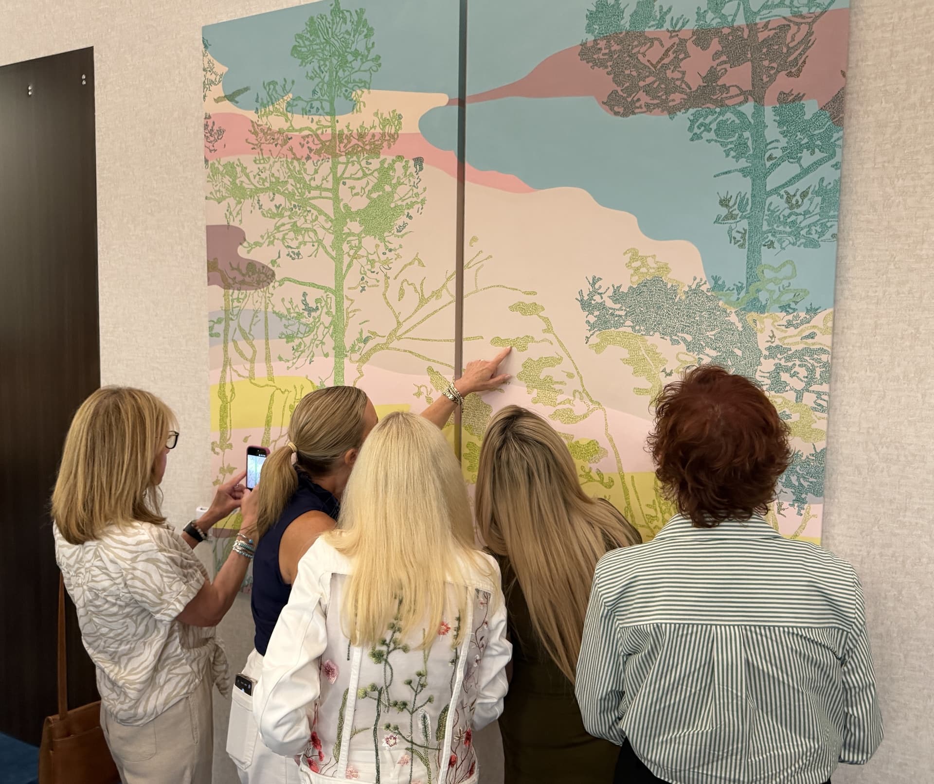 five people look at a mural