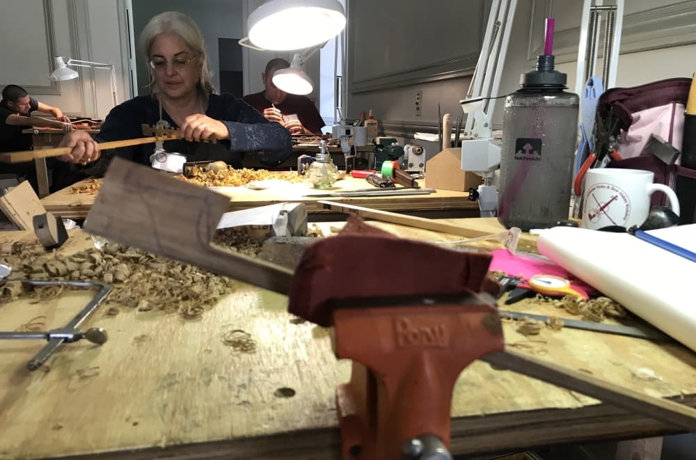 Owner Lori Faerber-Iacoletti repairs an instrument at a worktable.