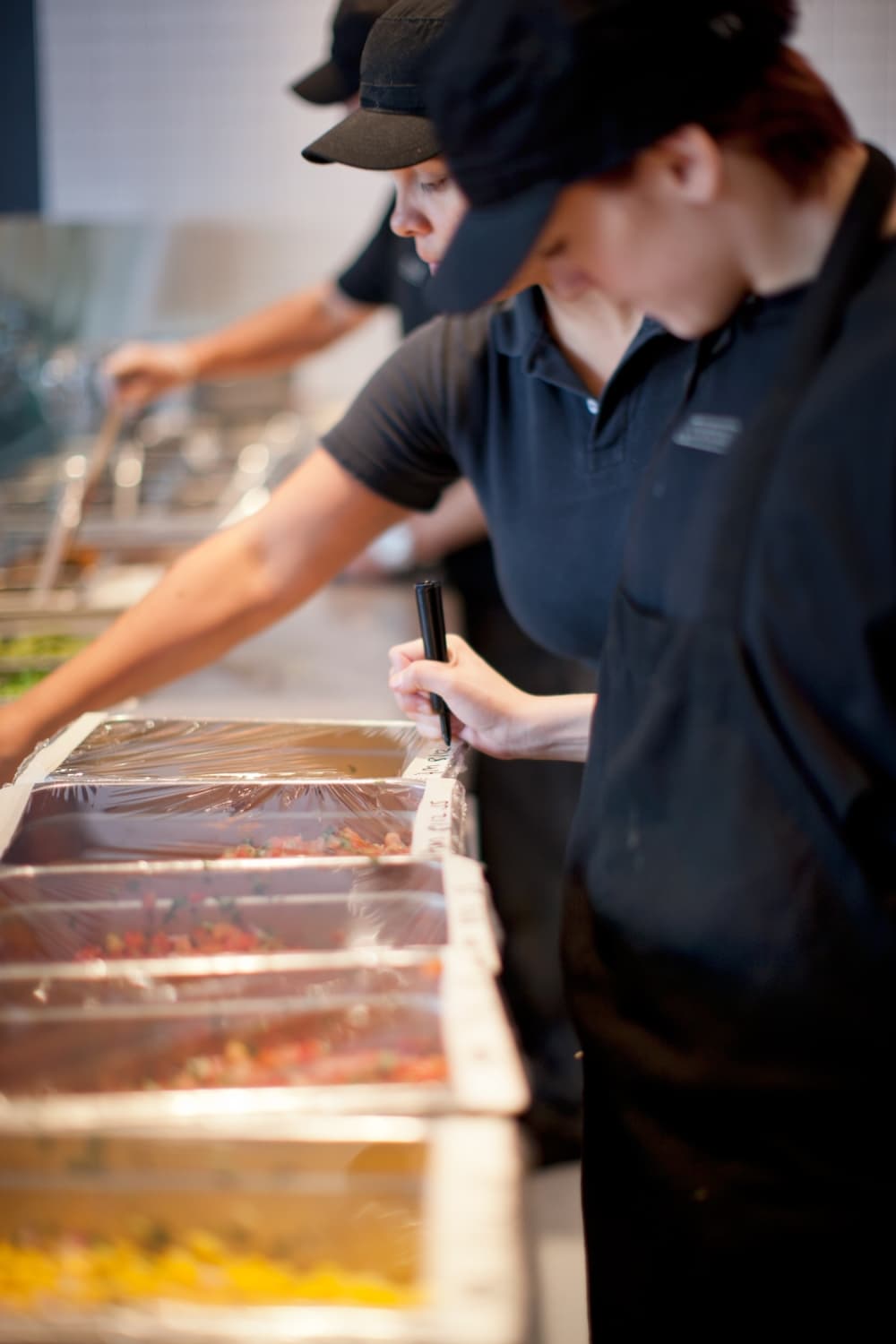 Chipotle team member sfill the food line.
