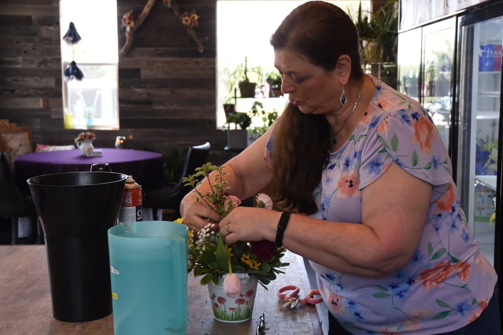 Woman designs floral arrangement.