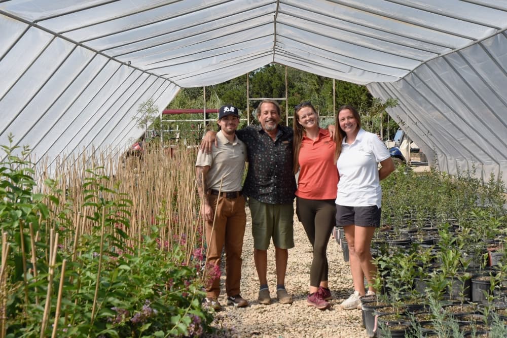 The image shows a group of people in a greenhouse.