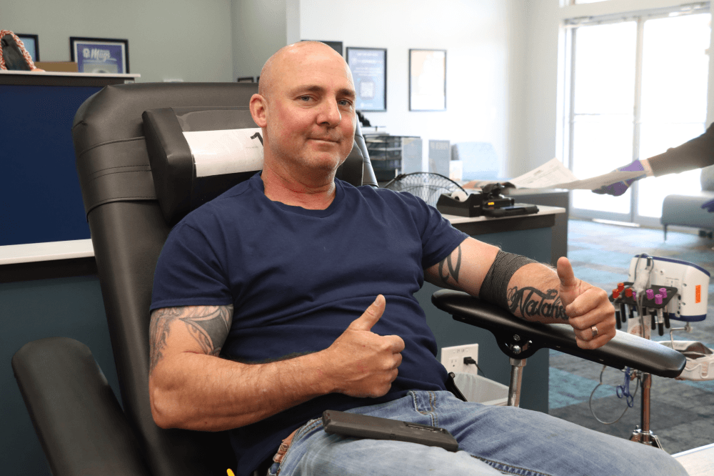 man holding thumbs up while getting blood drawn