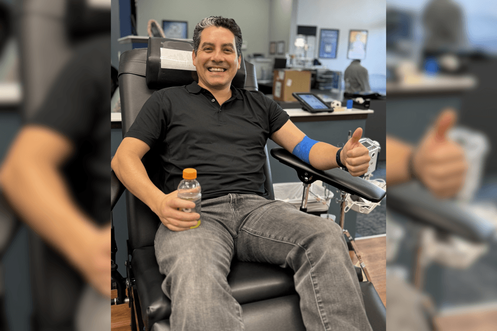man holding thumbs up and smiling while getting blood drawn
