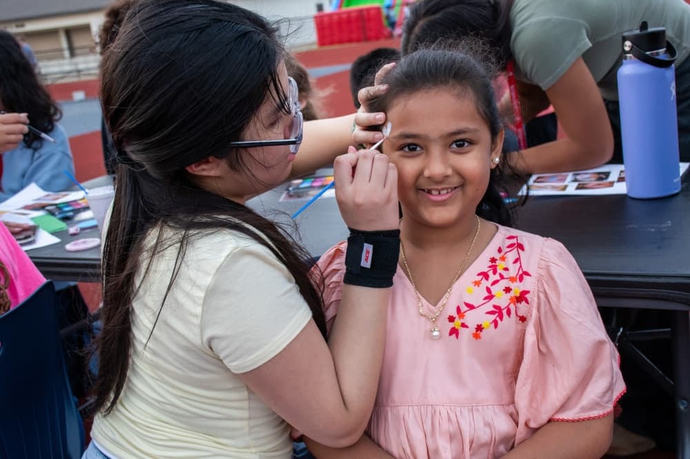 student painting another student's face at face painting booth