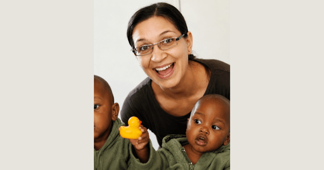 Smiling woman holding a rubber duck between two young children.