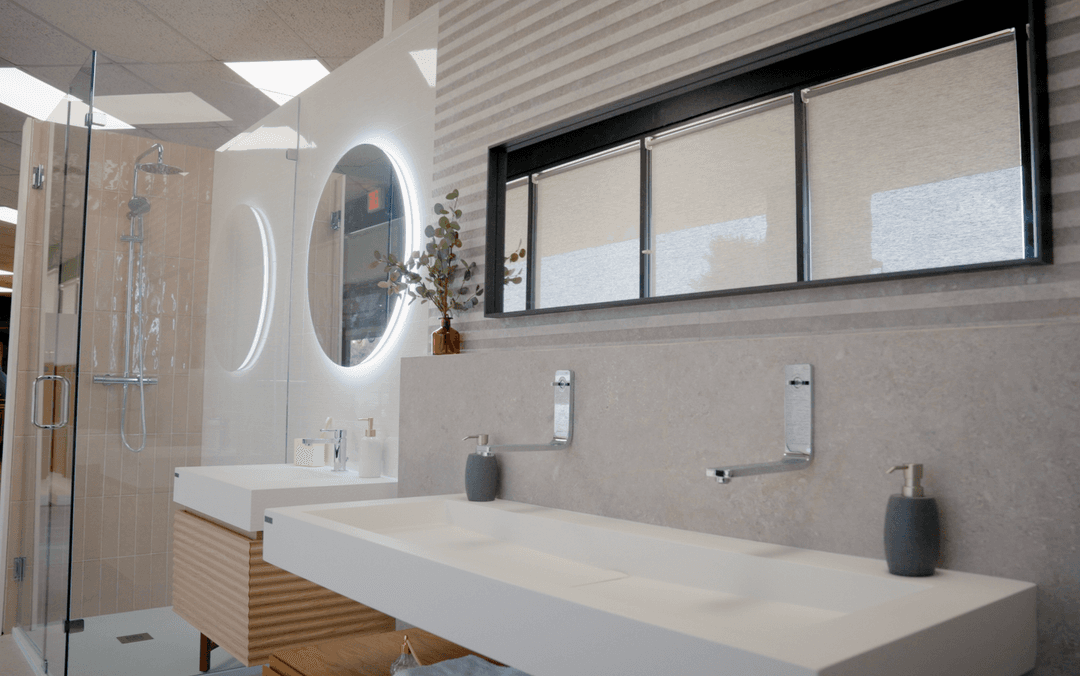 Modern bathroom with white sinks, wall-mounted faucets, round lit mirrors, glass shower, and eucalyptus plant.