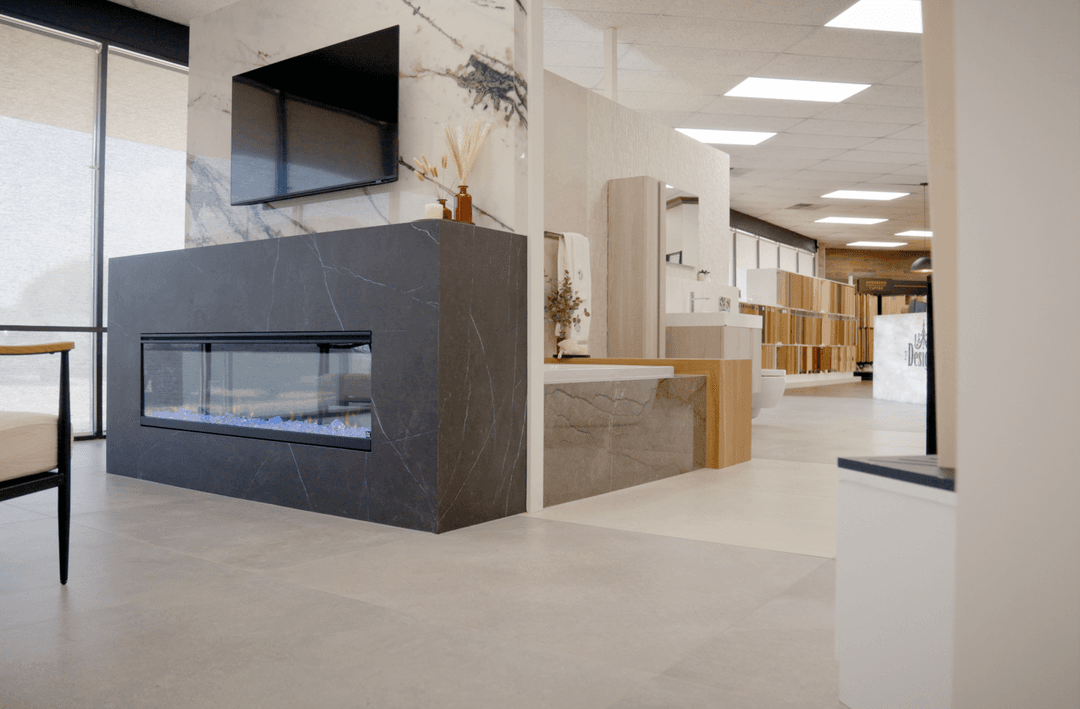Home design showroom featuring a dark stone fireplace with mounted TV, marble accents, and bathroom vanity displays.