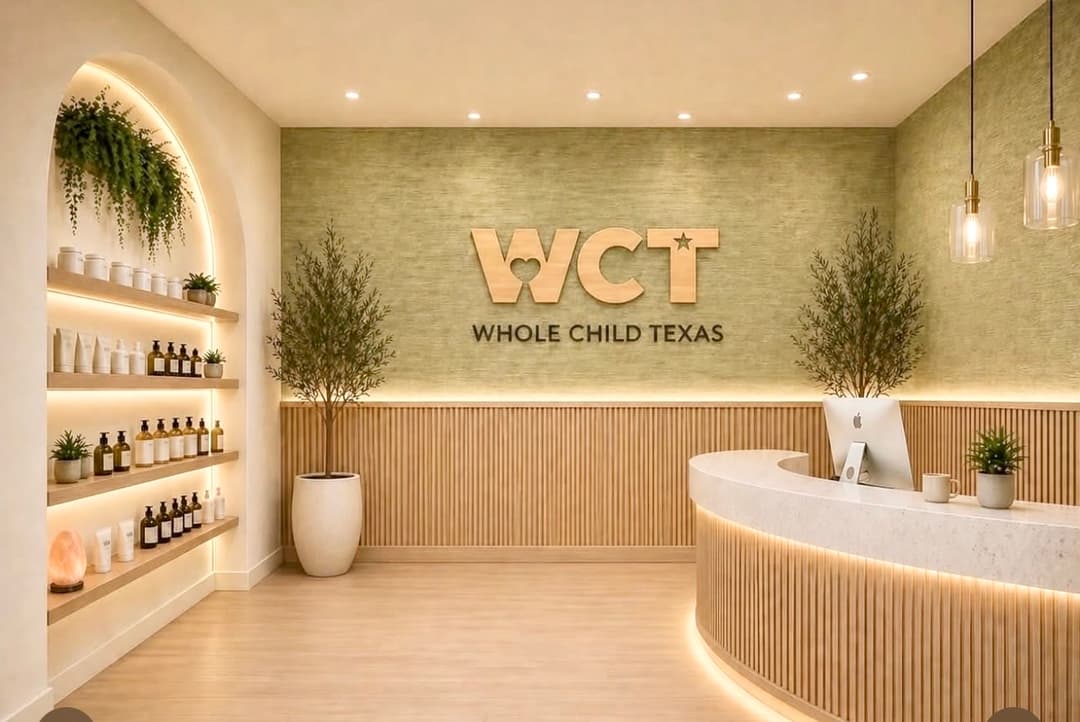 Modern Whole Child Texas lobby with reception desk, wood logo sign, plants, and shelves of products.