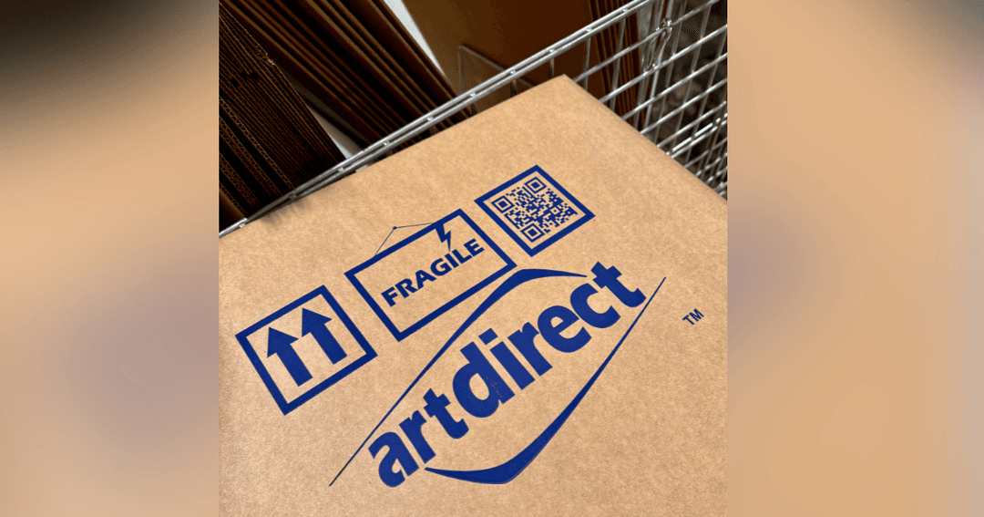 Cardboard box with blue "artdirect" logo, fragile and this-way-up symbols, and QR code.