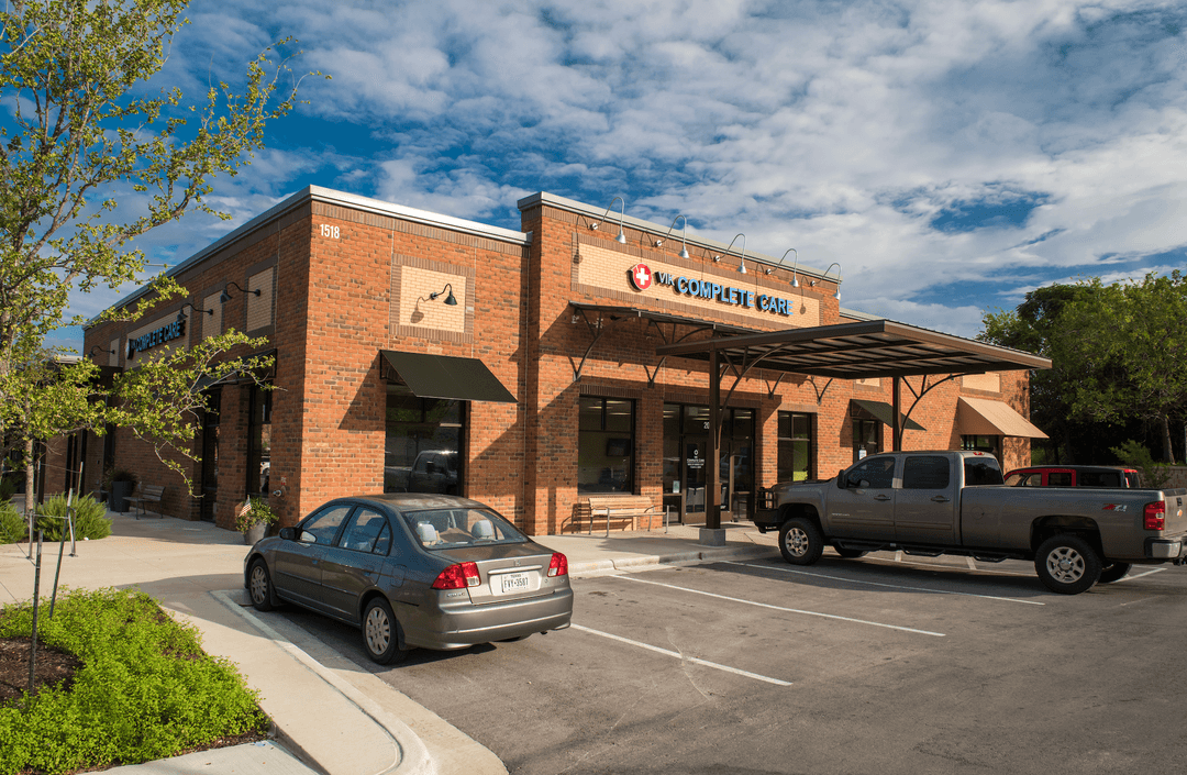 VIK Complete Care brick medical building with cars parked outside under a blue sky with clouds.
