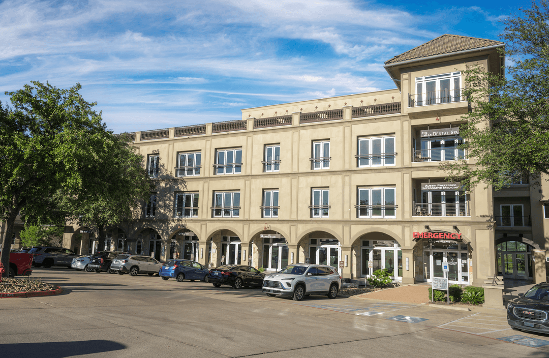 Multi-story medical building with dental spa, integrative medicine, and emergency care signs, with cars parked out front.