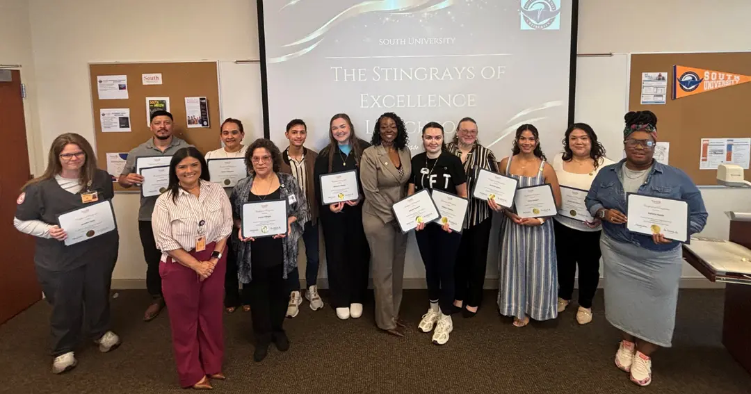 Group of South University award recipients holding certificates before a "Stingrays of Excellence" screen.