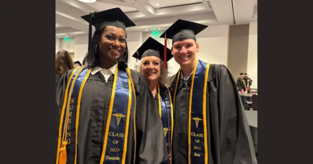 Three nursing graduates in caps and gowns with Class of 2025 stoles smile together at ceremony.