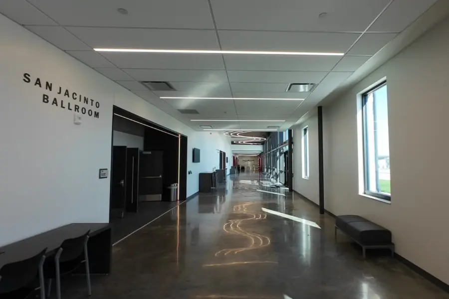 Empty modern hallway with polished floors, benches, and "San Jacinto Ballroom" text on the wall.