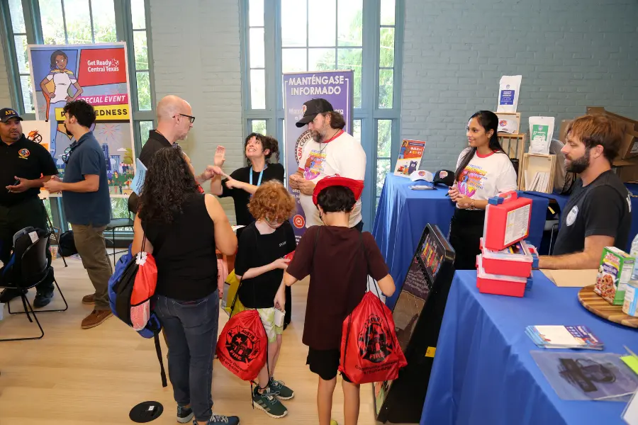 Families and staff at an emergency preparedness community event with information booths and giveaway bags.