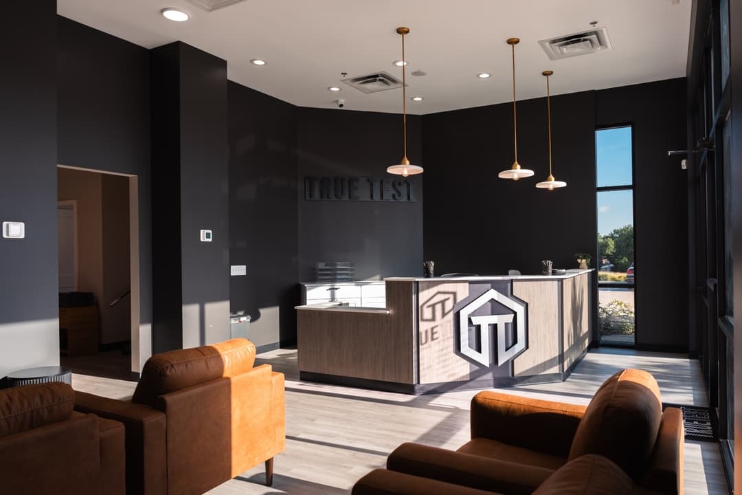 A reception area with black walls and tan arm chairs