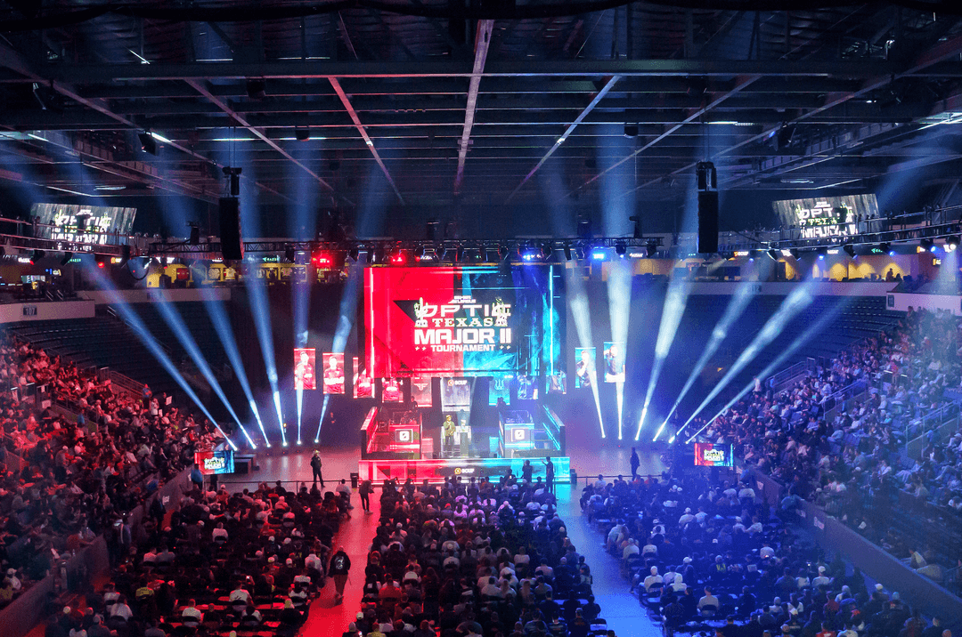 Packed arena at OpTic Texas Major II esports tournament with stage, spotlights and large crowd.
