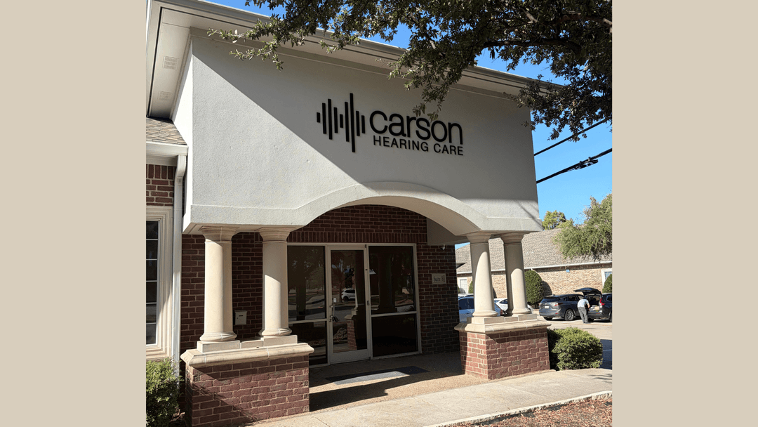 Exterior entrance of Carson Hearing Care, a brick building with columns and glass doors under a signed facade.