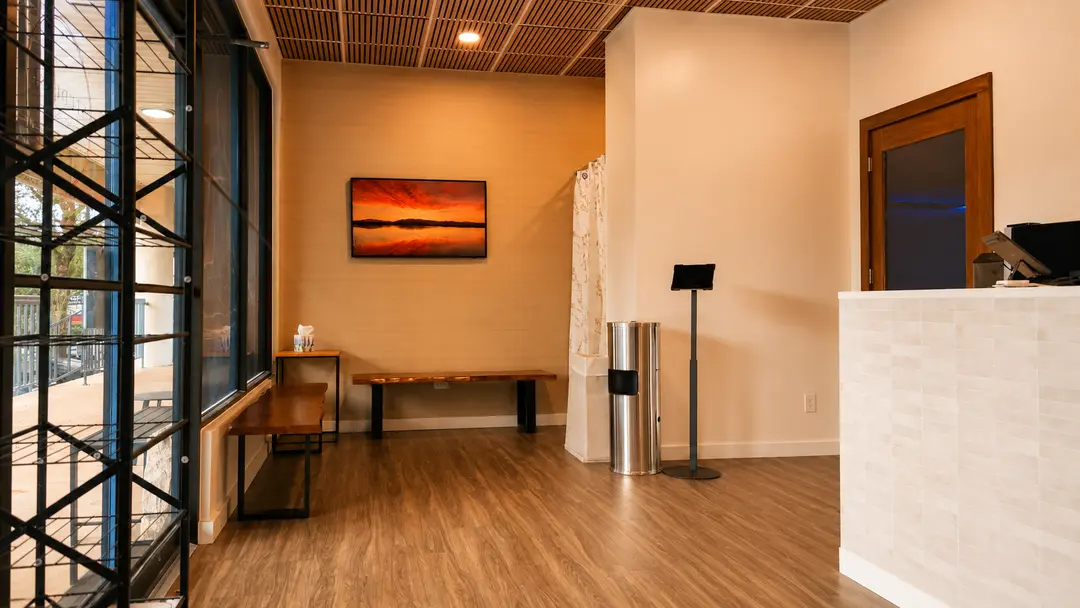 Modern office lobby with wooden benches, sunset artwork, tablet stand, and tiled reception desk.