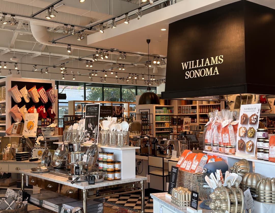 Williams Sonoma store interior with cookware, bakeware, utensils and food displays under a black branded sign.