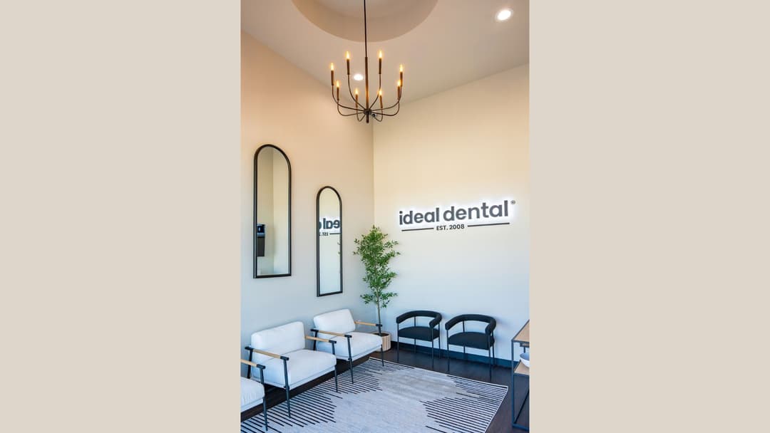 Ideal Dental waiting room with chairs, arched mirrors, chandelier and wall sign reading "ideal dental Est. 2008.