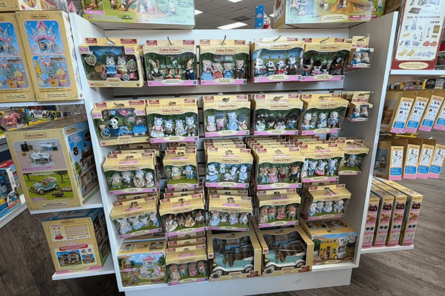 Store display shelves filled with boxed Calico Critters toy animal figures and playsets.