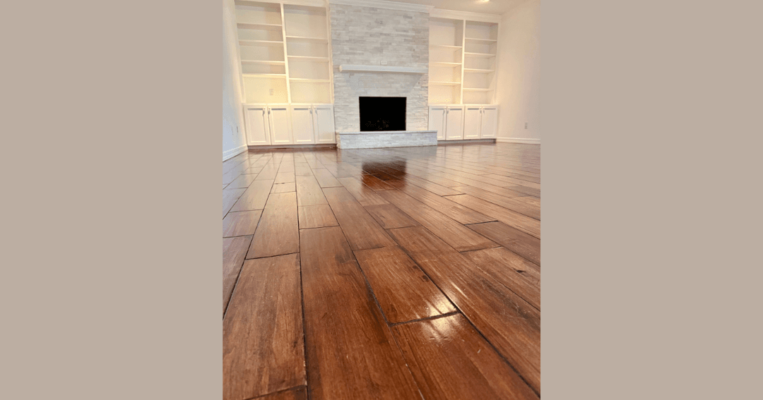 Empty living room with hardwood floors, stone fireplace, and white built-in shelves and cabinets.