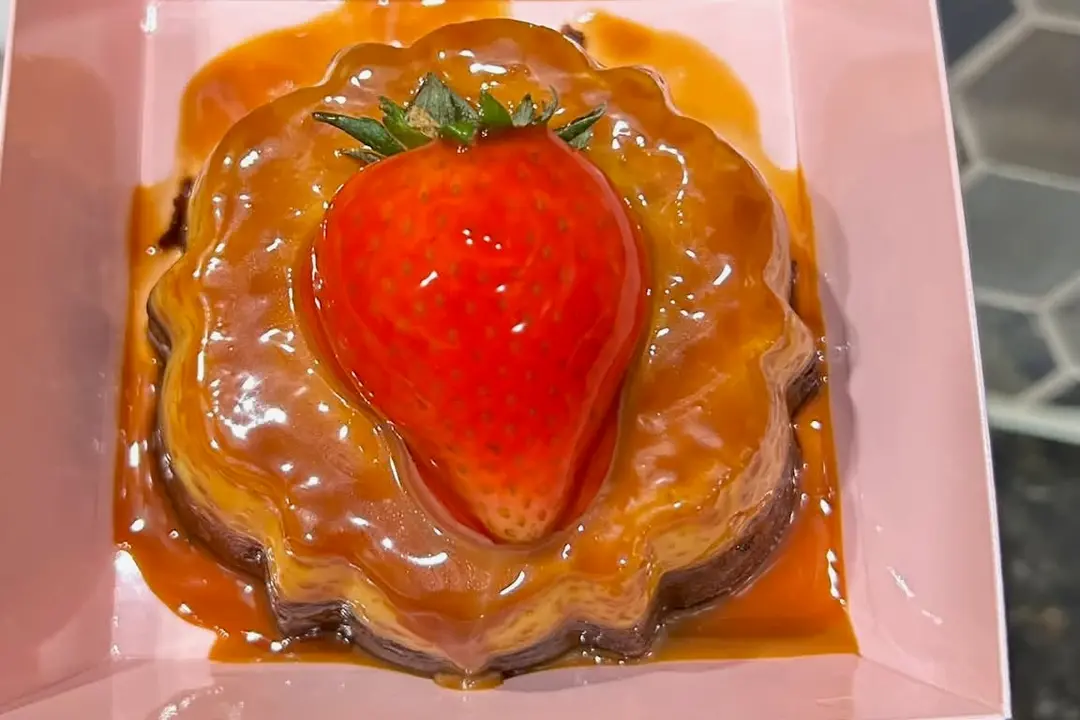 Caramel-glazed dessert topped with a whole fresh strawberry in a pink box.