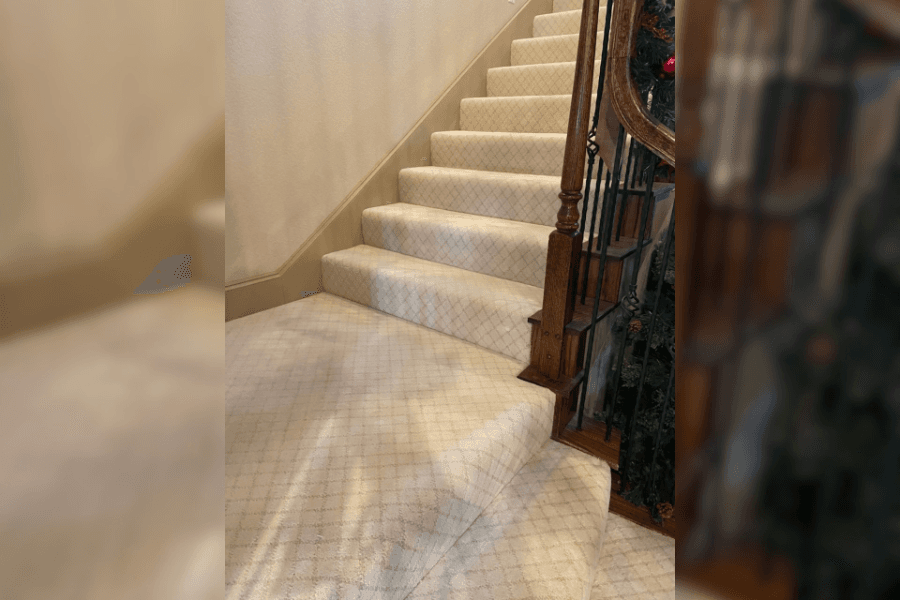 Beige diamond-patterned carpeted staircase with wooden banister and wrought-iron spindles, holiday garland nearby.