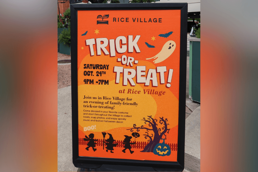 Orange sign for Rice Village Trick-or-Treat event, Saturday Oct. 24th, 4PM-7PM, with ghost and costumed kids.