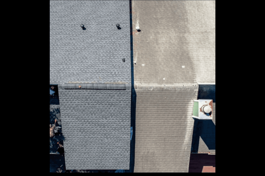 Aerial view of asphalt shingle roof with ridge line, showing new and weathered sections side by side.